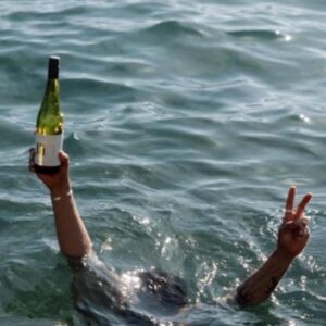 Une bouteille de vin blanc brandie hors de l’eau du lac